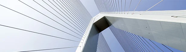 Upward perspective of modern building facades with clean, linear paneling converging toward the sky, highlighting sharp architectural lines against a clear blue background.